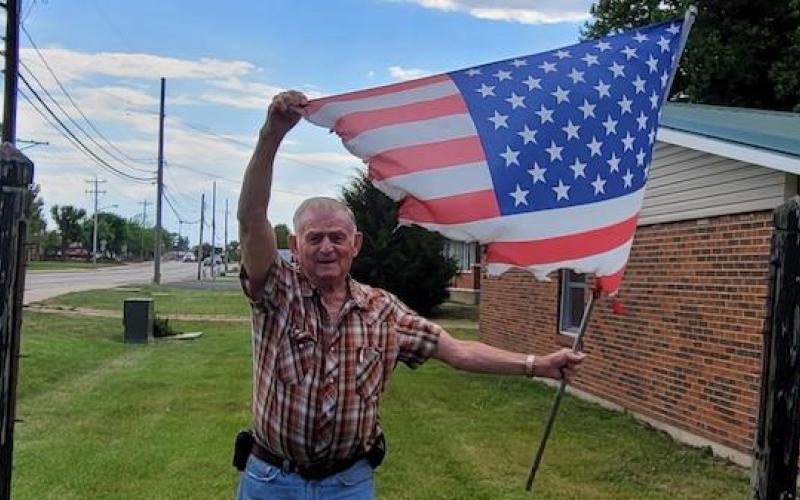 John Baxter holds up a flag that was burned Article Image Alt Text