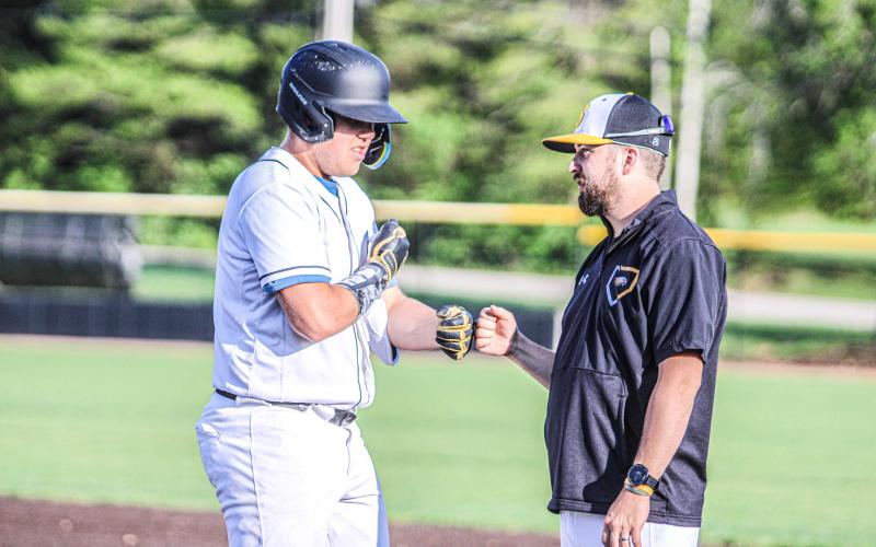 BIG MITCH. Mitchell Garner fist-bumps coach Kris Poore after sliding to first. Photo by Wyatt Hardy Article Image Alt Text