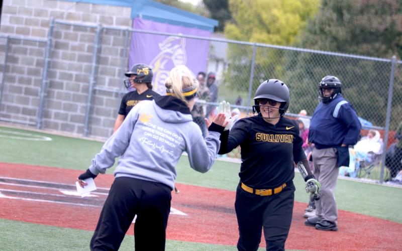 HIGH-FIVE. After sophomore Evelynn Harris scored a run against Ursuline, head coach Ashley Crump congratulated her with a high-five. Up-and-coming star Harris has also been explosive in junior varsity. Photo by Wyatt Hardy. Article Image Alt Text