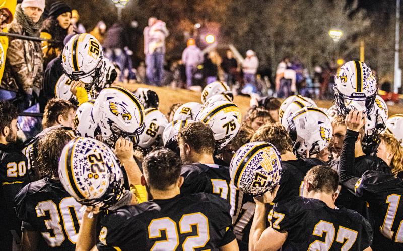 ONE LAST RIDE. The Eagles huddle together for the final time, raising their helmets to perform their last “Victory Chant” after they lost the District Championship. Photo by Wyatt Hardy. Article Image Alt Text